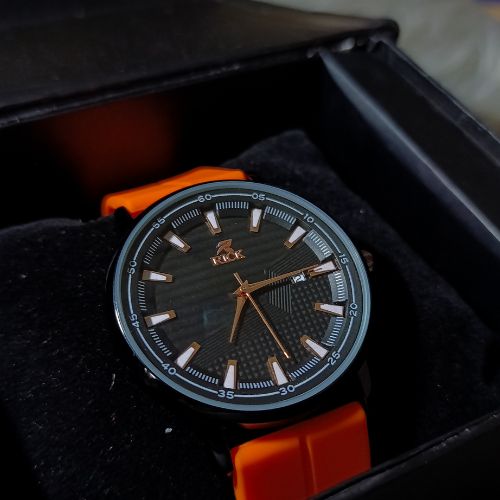 Close-up of black dial on Rick orange strap men’s watch