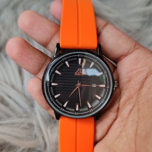 Rick men’s watch with black dial and orange strap worn on wrist