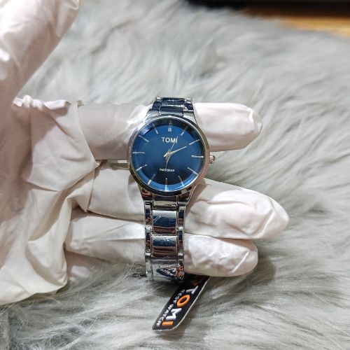 Modern TOMI couple watch set with polished stainless steel bracelet and classic blue dial in men’s and women’s sizes.