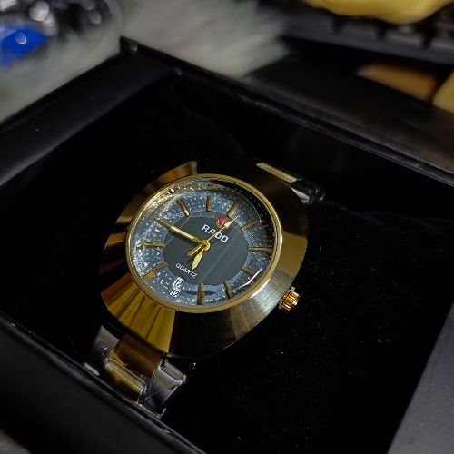 Classic Rado DiaStar men’s quartz watch featuring gold-toned case, black dial, and durable stainless steel strap.